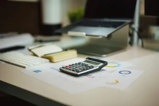 a calculator sitting on top of a table next to a laptop by Jakub Żerdzicki courtesy of Unsplash.