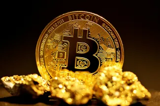 a bitcoin sitting on top of a pile of gold nuggets by Kanchanara courtesy of Unsplash.