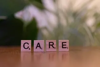 A wooden block spelling care on a table by Markus Winkler courtesy of Unsplash.