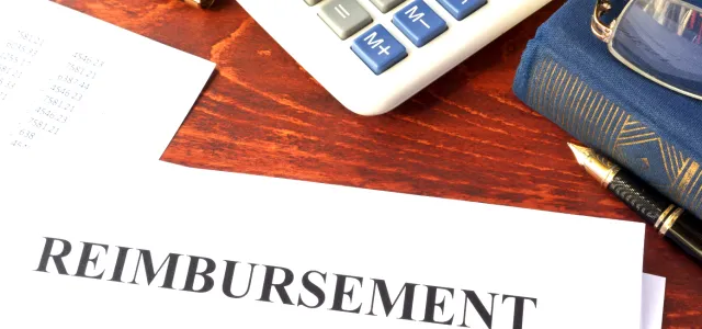 Image featuring a calculator, book, fancy pen, and a doucment titled reimbursement.