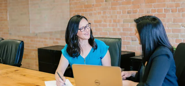 woman in teal t-shirt sitting beside woman in suit jacket by Amy Hirschi courtesy of Unsplash.