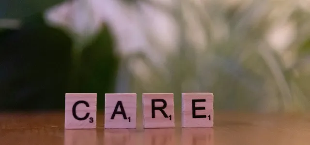 A wooden block spelling care on a table by Markus Winkler courtesy of Unsplash.